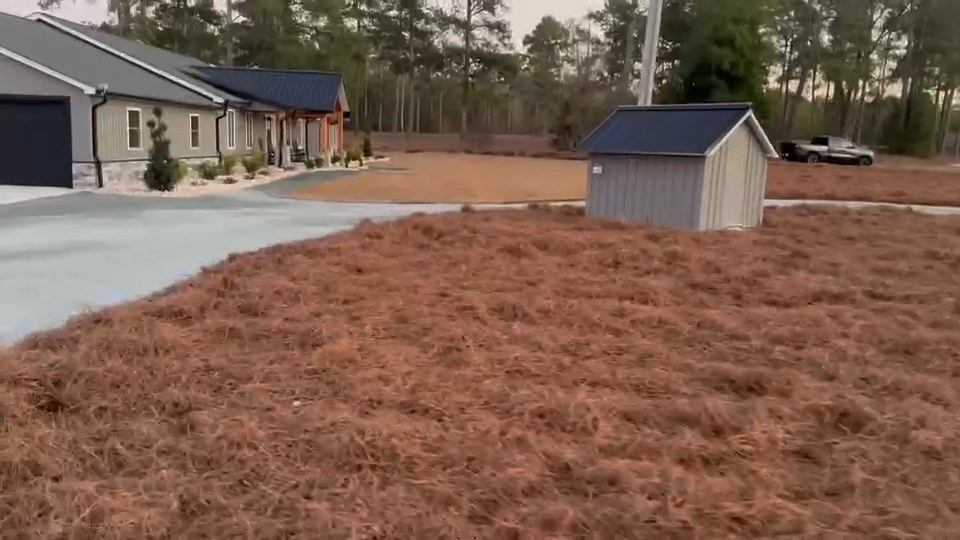 Pine straw beds and yard work beside a home